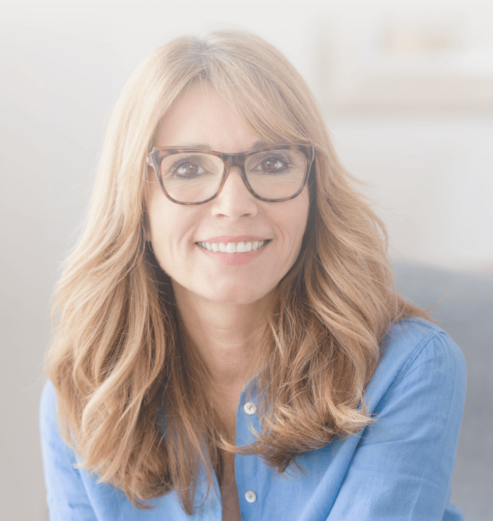 A smiling woman in her fifties wearing glasses